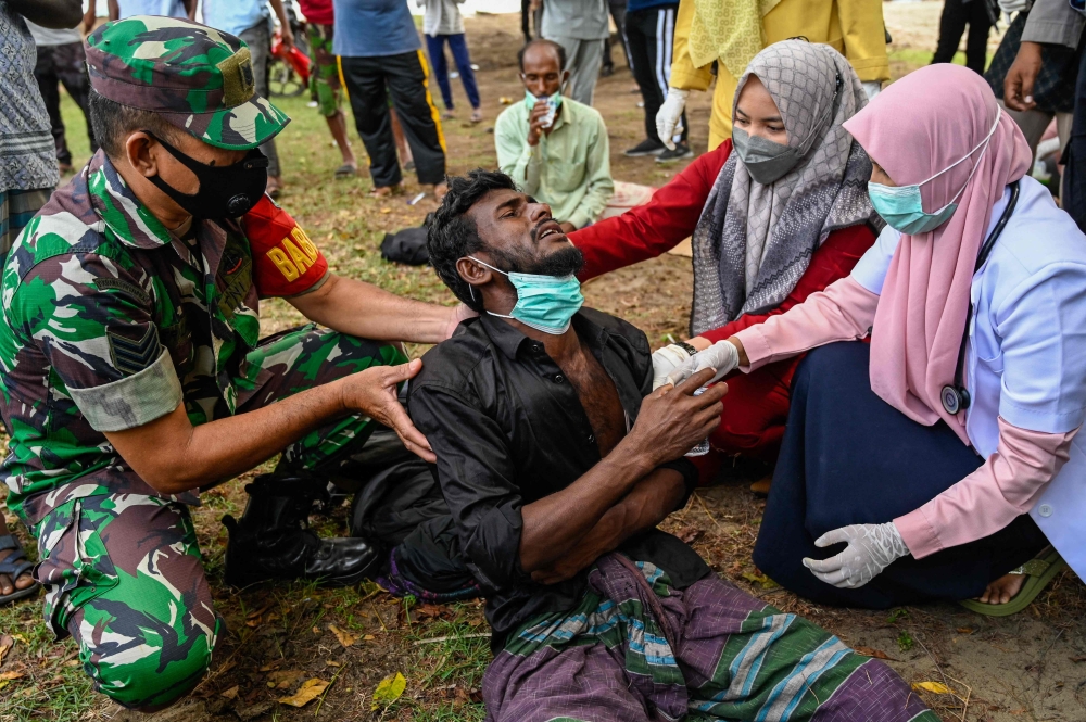 Health workers check a Rohingya refugee who was feeling sick after his arrival by boat in Krueng Raya, Indonesia's Aceh province on December 25, 2022. (Photo by Chaideer Mahyuddin / AFP)
