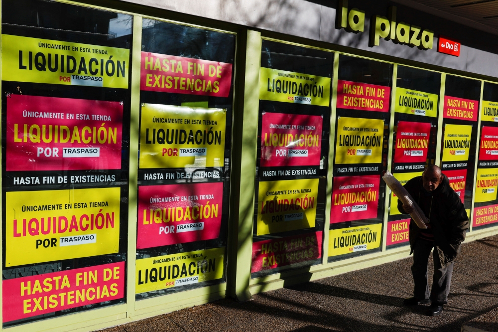 A customer exits a supermarket with posters announcing closing down sales, as the Spanish government announces measures to battle inflation, in Madrid, Spain, December 27, 2022. (REUTERS/Violeta Santos Moura)