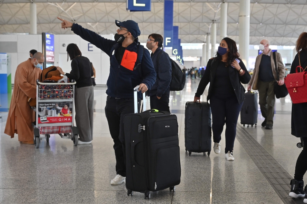 Passengers head to check-in counters at the international airport in Hong Kong on December 28, 2022. (Photo by Peter PARKS / AFP)