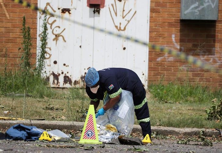 A forensic pathologist collects human remains at the scene where a gas tanker exploded in Boksburg near Johannesburg, South Africa, on December 24, 2022. REUTERS/Sumaya Hisham

