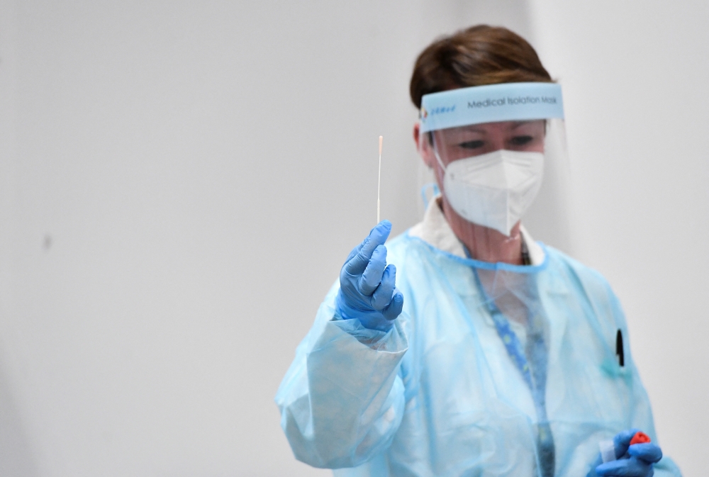A health worker wearing personal protective equipment (PPE) holds a swab in her hand to conduct tests for the coronavirus disease (COVID-19), after Italy has ordered COVID-19 antigen swabs and virus sequencing for all travellers coming from China, where cases are surging, at the Malpensa Airport in Milan, Italy, on December 29, 2022. REUTERS/Jennifer Lorenzini
