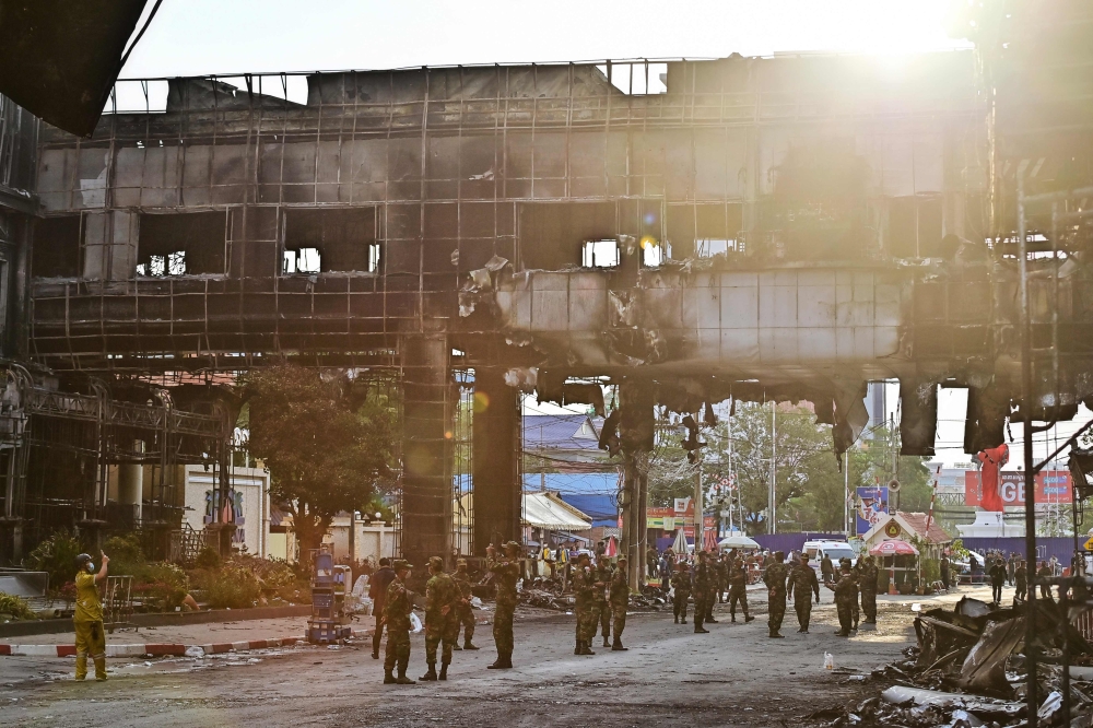 Cambodian soldiers patrol the destroyed part of the Grand Diamond City hotel-casino after a fire in Poipet on December 30, 2022. (Photo by Lillian Suwanrumpha / AFP)