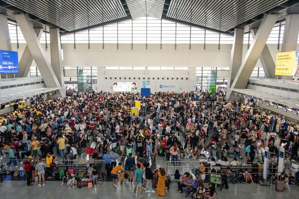 Passengers wait for information about their flights at terminal 3 of Ninoy International Airport in Pasay, Metro Manila on January 1, 2023. (Photo by KEVIN TRISTAN ESPIRITU / AFP)

