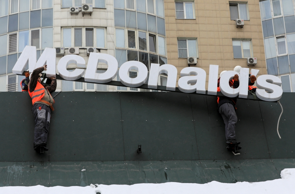 Workers remove the logo signage from a restaurant of McDonald's in Almaty, Kazakhstan, January 6, 2023. (REUTERS/Pavel Mikheyev)