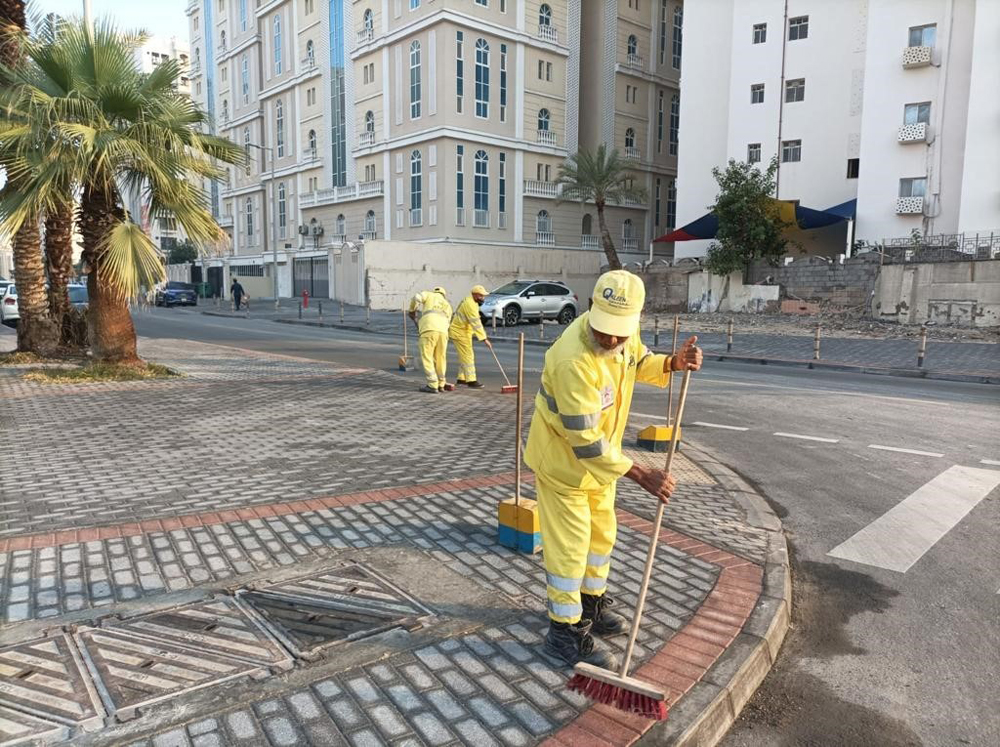 Municipality employees cleaning a road.