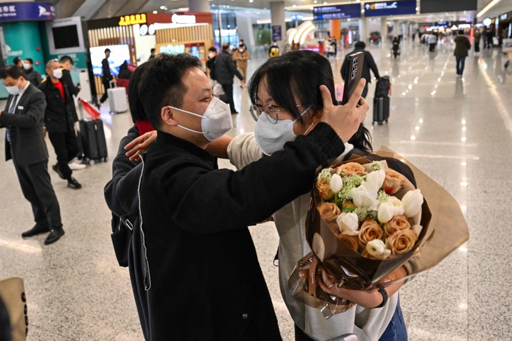 A passenger receives a hug while leaving the arrival area of international flights at the Shanghai Pudong International Airport, in Shanghai on January 8, 2023.(Photo by Hector Retamal / AFP)