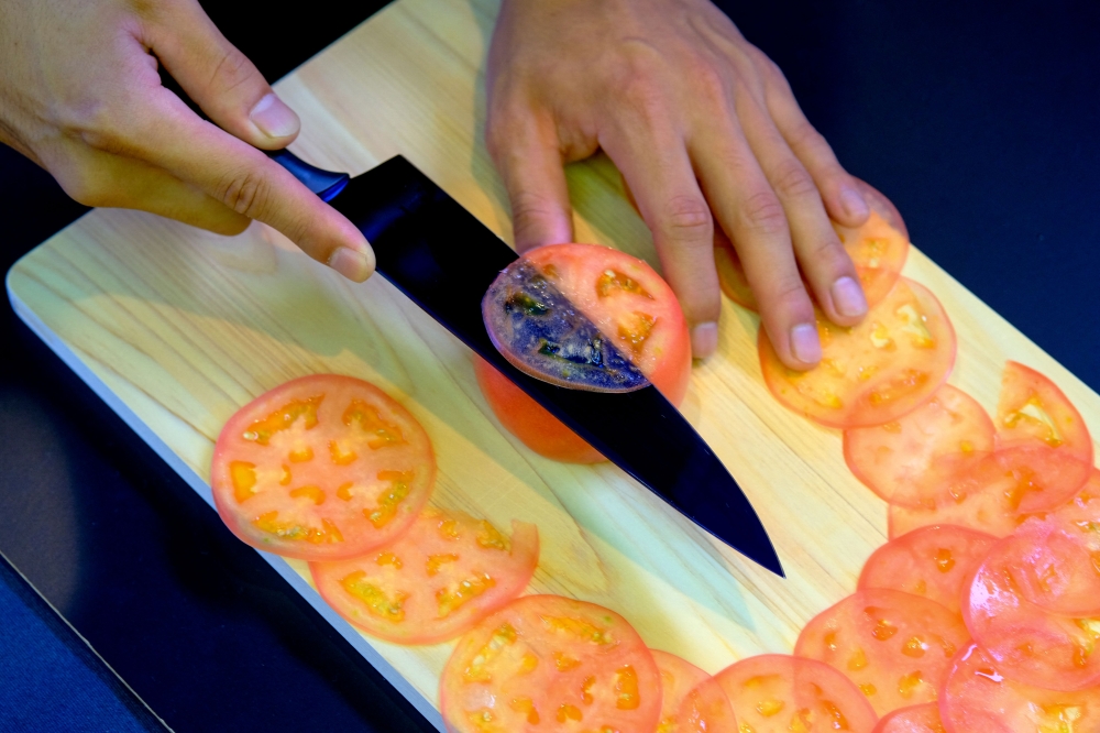 This picture taken on September 2, 2022 shows a demonstration to test the sharpness of a knife with a tomato at a factory of Sumikama Cutlery in Seki, Gifu prefecture.(Photo by Kazuhiro Nogi / AFP)