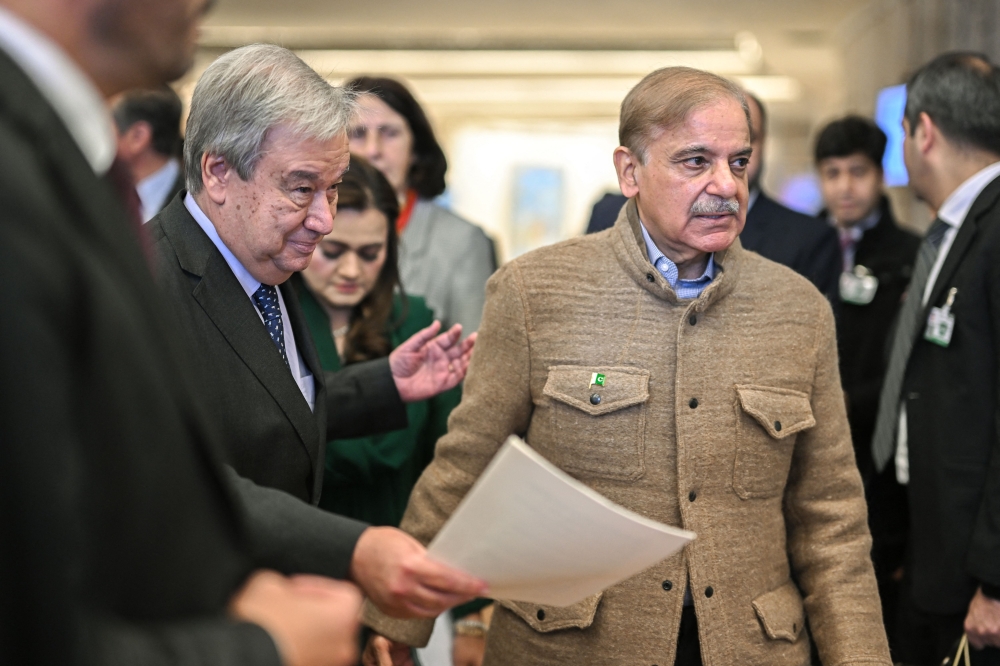 UN Secretary-General Antonio Guterres (left) arrives with Pakistan's Prime Minister Shehbaz Sharif to a statement on Pakistan's Resilience to Climate Change conference in Geneva on January 9, 2023. (Photo by Fabrice COFFRINI / AFP)