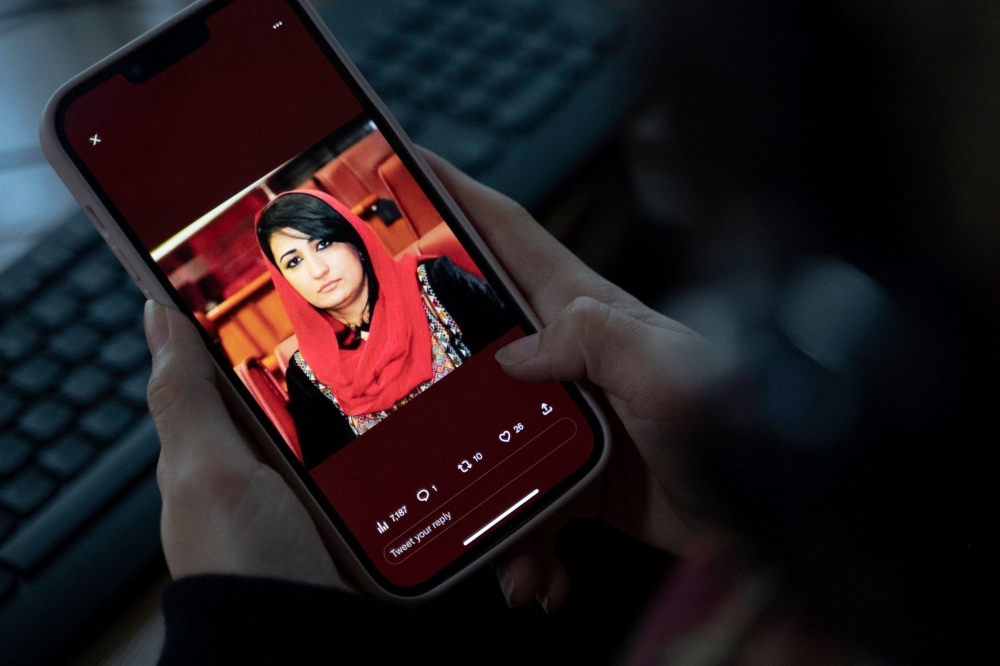 A woman looks at a picture of former Afghan lawmaker Mursal Nabizada on her mobile phone, who was shot dead by gunmen last night at her house in Kabul on January 15, 2023. (Photo by Wakil Kohsar / AFP)