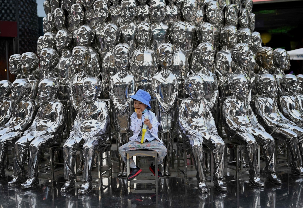 In this file photo taken on June 1, 2021 a boy sits on a chair amongst sculptures on display at a shopping centre on International Children's Day in Beijing.  (Photo by Noel Celis / AFP)