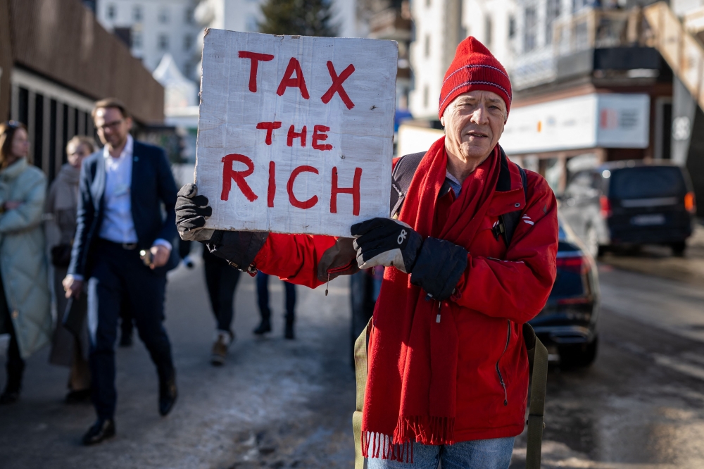 Phil White, a British millionaire poses with a placard reading: 