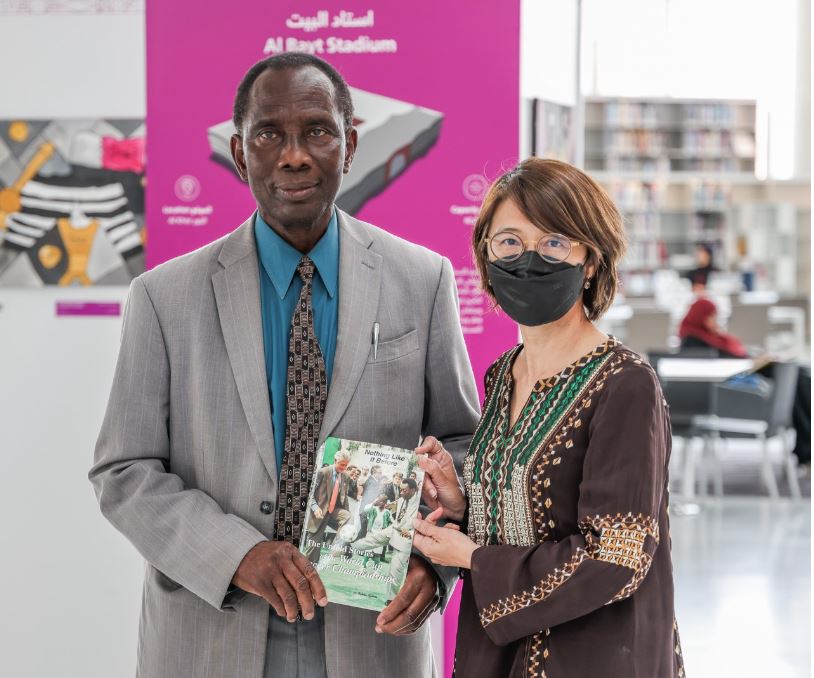 Qatar National Library executive director, Tan Huism (right) receives a donation of a book from the author, Fidelis Iyebote.