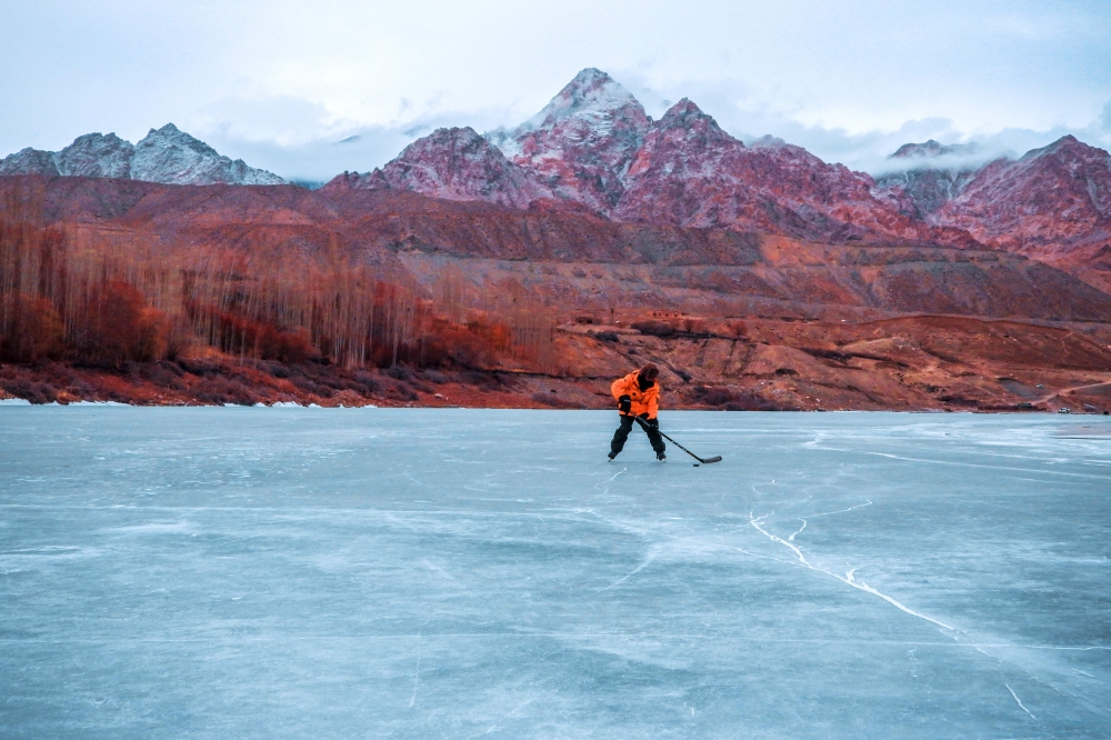 In this picture taken on January 20, 2023, an ice hockey player chases the puck on the frozen river Indus in Leh city, India. (Photo by Mohd Arhaan Archer / AFP)