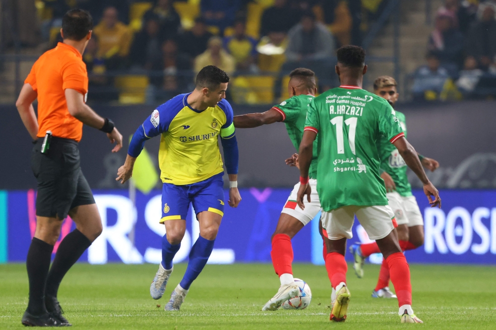 Nassr's Cristiano Ronaldo (second left) fights for the ball with Ettifaq's Saudi defender Saeed al-Mowalad the Saudi Pro League football match between Al-Nassr and Al-Ettifaq at the King Fahd Stadium in the Saudi capital Riyadh on January 22, 2023. (Photo by Fayez NURELDINE / AFP)