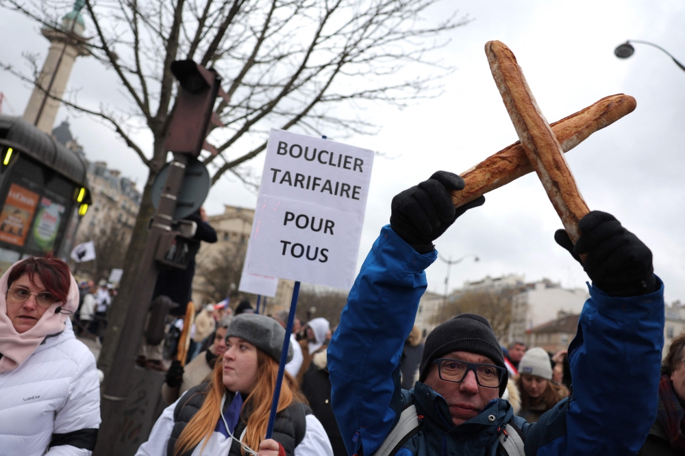A hold up two crossed baguettes during a protest organised by the collective for the survival of bakers and crafts artisans against the rising energy costs, as they march from from Place de la Nation to Bercy, in Paris on January 23, 2023. (Photo by Thomas SAMSON / AFP)
 