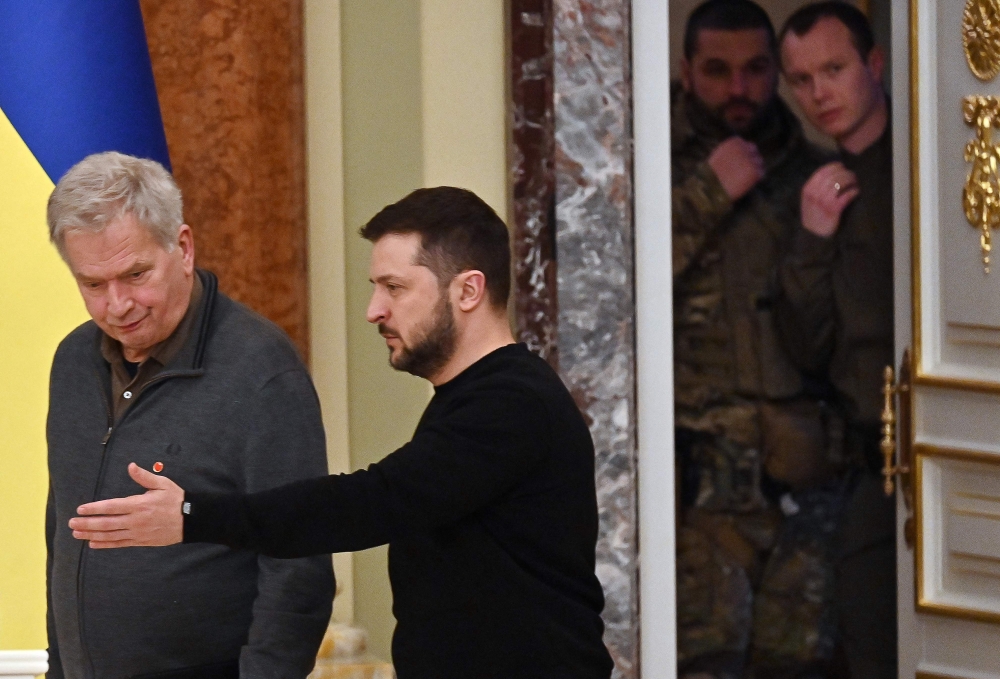 Ukrainian security officers look out from a door as Ukrainian President Volodymyr Zelensky greets his Finnish counterpart Sauli Niinisto (left) to their joint press conference following talks in Kyiv, on January 24, 2023, amid Russia's military invasion on Ukraine. (Photo by Sergei Supinsky / AFP)