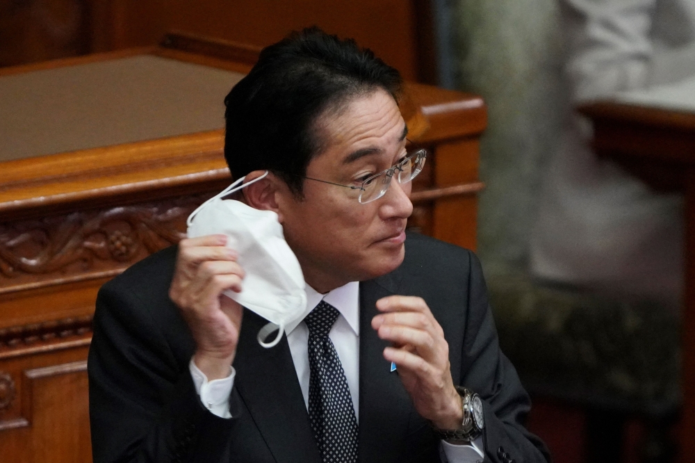 Japanese Prime Minister Fumio Kishida removes his face mask before his speech during a plenary session of the upper house of parliament in Tokyo on January 27, 2023. (Photo by Kazuhiro Nogi / AFP)