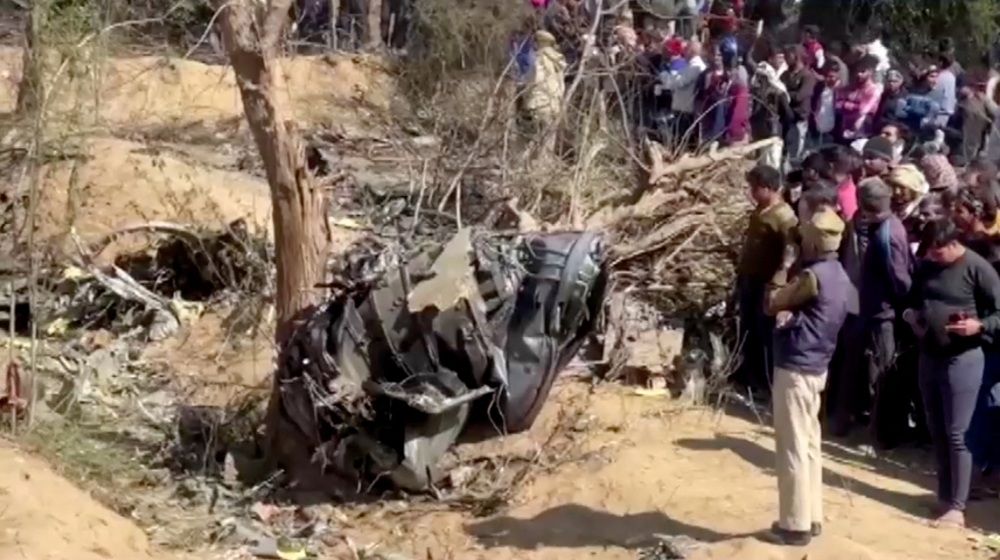People gather around the debris of a crashed aircraft in Bharatpur, Rajasthan, India, January 28, 2023 in this screen grab obtained from a handout video. ANI/Handout via Reuters
