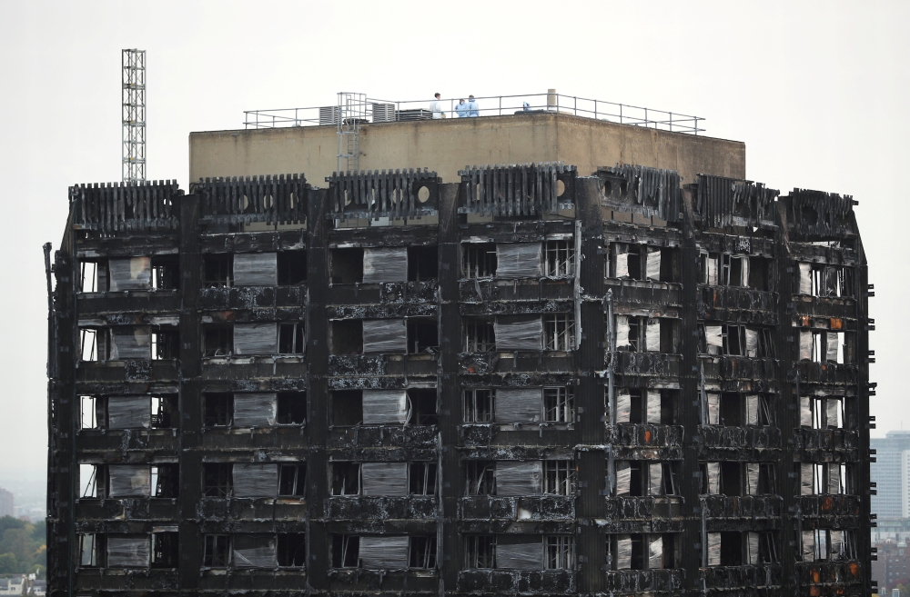 Workers stand on the roof of the burnt out remains of the Grenfell tower in London, Britain, on October 16, 2017. File Photo / Reuters
