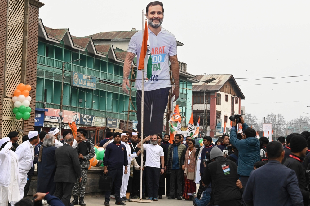Indian Congress leader Rahul Gandhi (left) along with sister Priyanka Gandhi hoists the Indian national flag during the 'Bharat Jodo Yatra' march in Srinagar on January 29, 2023. (Photo by TAUSEEF MUSTAFA / AFP)