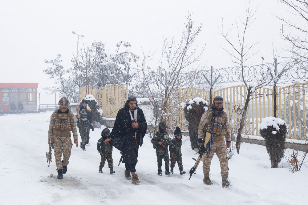 Taliban soldiers with their children dressed in military uniforms and holding plastic weapons, walk on a snow-covered street on a snowy day in Kabul, Afghanistan, on January 29, 2023. REUTERS/Ali Khara