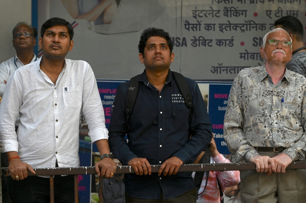 Onlookers watch a digital broadcast showing India's Finance minister Nirmala Sitharaman presenting the union budget outside the Bombay Stock Exchange (BSE) in Mumbai on February 1, 2023. (Photo by Indranil Mukherjee / AFP)