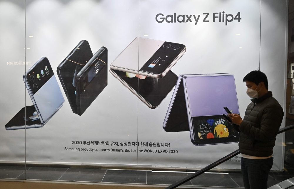 A man walks past an advertisement for the Samsung Galaxy Z Flip4 smartphone at the company's Seocho building in Seoul on January 31, 2023. (Photo by Jung Yeon-je / AFP)