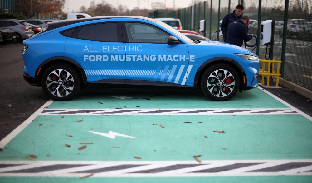 FILE PHOTO: Workers plug in an electric Ford Mustang Mach-e electric vehicle during a press event at the Ford Halewood transmissions plant in Liverpool, Britain, December 1, 2022. REUTERS/Phil Noble