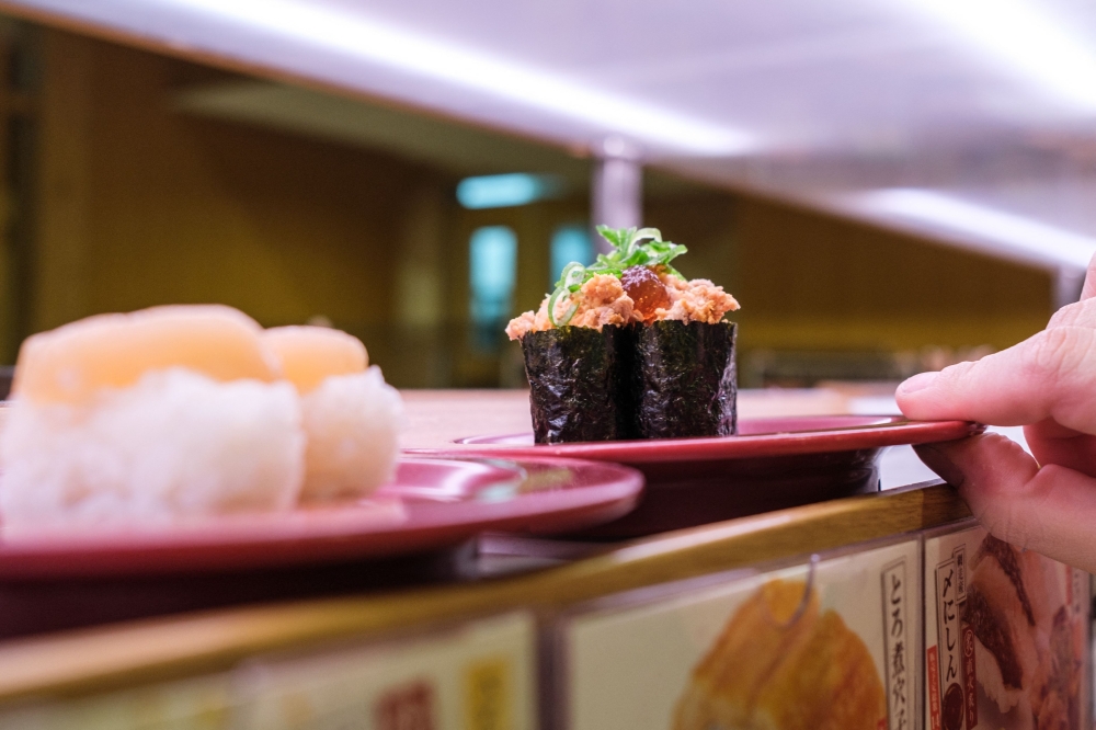 This picture shows plates of sushi on a conveyor belt at a sushi chain restaurant in Tokyo on February 3, 2023. (Photo by Philip Fong / AFP)
