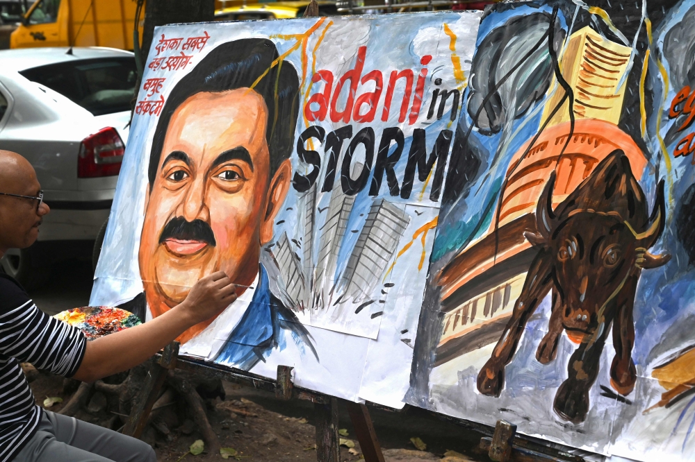 Art school teacher Sagar Kambli gives final touches to a painting of Indian businessman Gautam Adani highlighting the ongoing crisis of the Adani group in Mumbai on February 3, 2023. (Photo by INDRANIL MUKHERJEE / AFP)