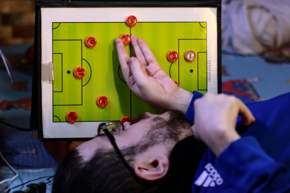 Amer Abo Nawas holds a board in the shape of a football field, used for explaining to his followers on the social media the plans of the coaches and the roles of the players on the field during a football match, at his home in Zarqa, 30km (18 miles) from Jordan's capital, Amman, on January 23, 2023. Photo by Khalil MAZRAAWI / AFP