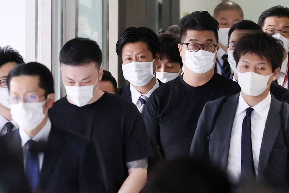 Toshiya Fujita (2nd L) and Kiyoto Imamura (front 2nd R, with glasses), members of a group of suspects believed to be behind a spate of robberies and telephone fraud cases across Japan, are escorted upon their arrival following their deportation from the Philippines at Narita International Airport in Chiba prefecture, outside Tokyo, on February 7, 2023.