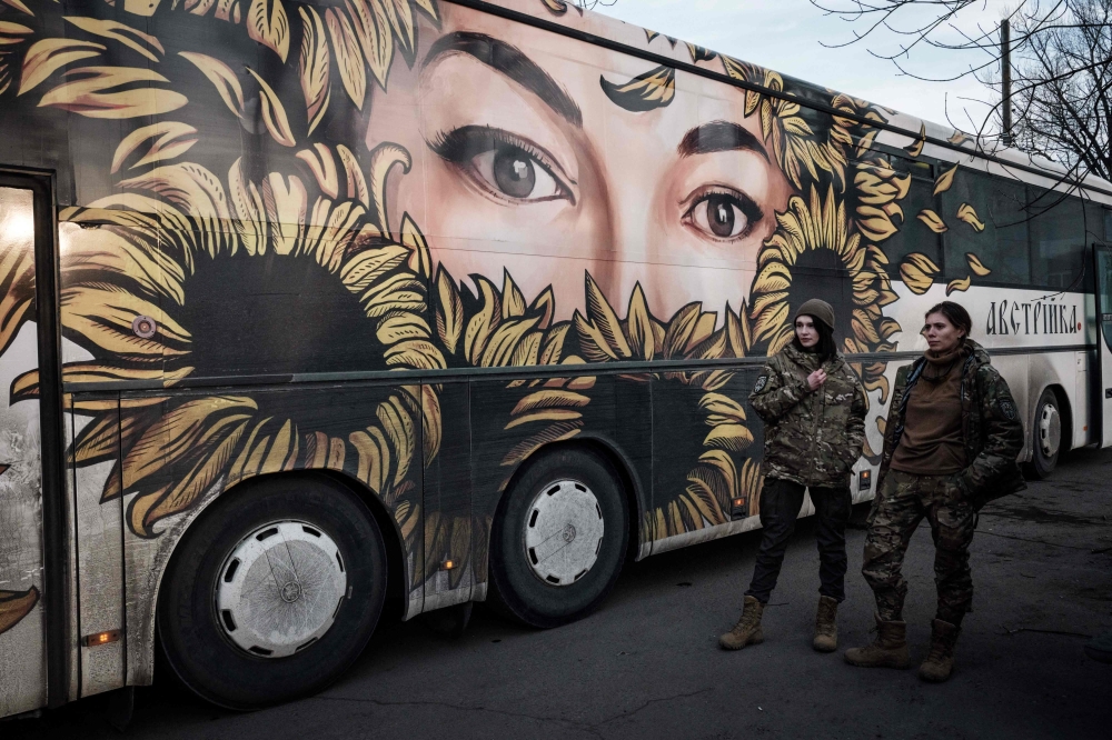 Ukrainian Poet Olena Herasymyuk (L) and Anna Skolbushevska waits for patients outside the bus for medical evacuations of the volunteer medical battalion Hospitallers, which helps with medical evacuations of wounded Ukrainian servicemen in Donetsk region on February 11, 2023, amid the Russian invasion of Ukraine. Photo by YASUYOSHI CHIBA / AFP