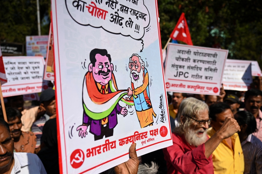 Communist Party of India (CPI) activists hold placards as they shout slogans against central government during a protest in Mumbai on February 13, 2023, calling for an enquiry into allegations of major accounting fraud at Adani, the country's biggest conglomerate. (Photo by Punit PARANJPE / AFP)