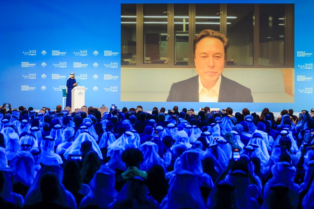 UAE Minister of Cabinet Affairs Mohammad al-Gergawi (L-on stage) speaks with Elon Musk attending the World Government Summit virtually in Dubai on February 15, 2023. (Photo by Karim SAHIB / AFP)