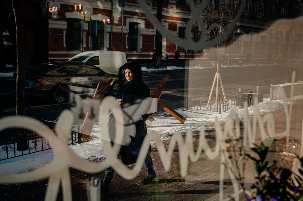 This photograph taken on February 8, 2023 shows a woman walking down a street next anti-tank hedgehogs in downtown Kyiv, amid the Russian invasion of Ukraine. (Photo by Dimitar DILKOFF / AFP)