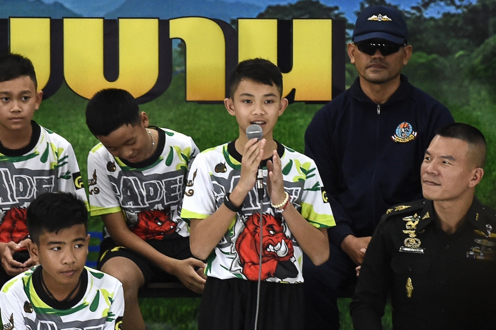 In this file photo taken on July 18, 2018 Duangpetch Promthep (C), one of the 12 boys rescued from deep inside a Thai cave after being trapped for more than a fortnight, speaks during a press conference in Chiang Rai following their discharge from hospital. Photo by LILLIAN SUWANRUMPHA / AFP