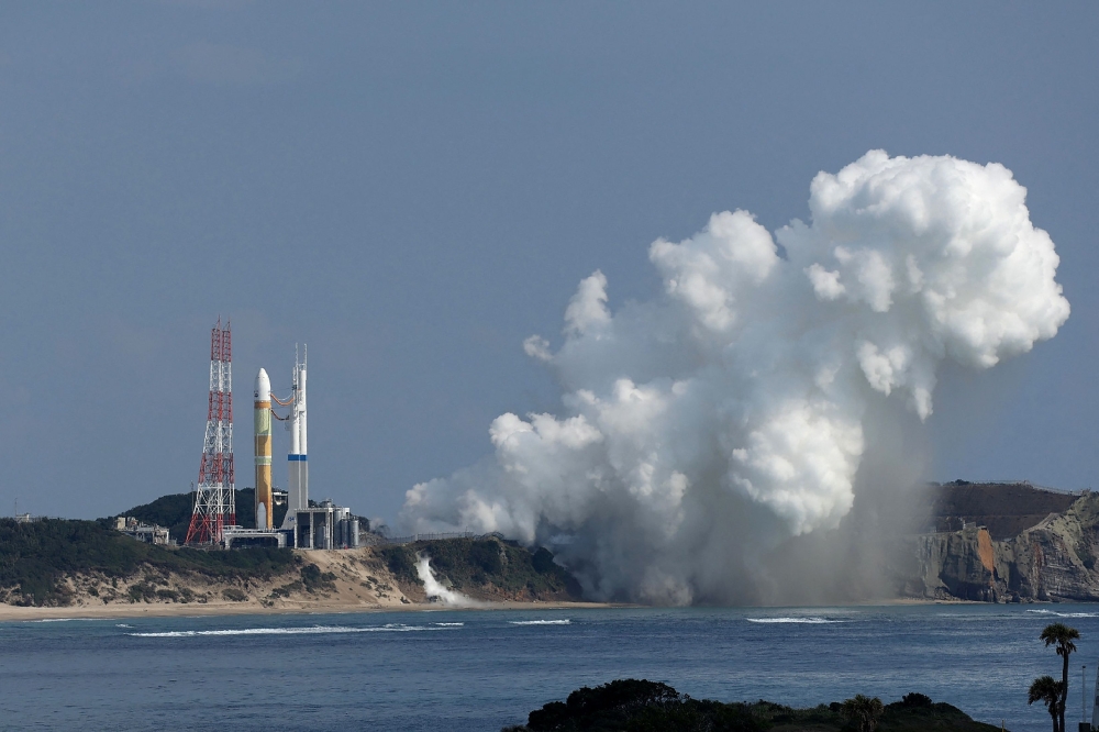 White smoke emerges from the main engines of the next-generation H3 rocket (L) as it fails to lift off the launch pad at the Tanegashima Space Center in southwestern Japan on February 17, 2023. Photo by JIJI Press / AFP