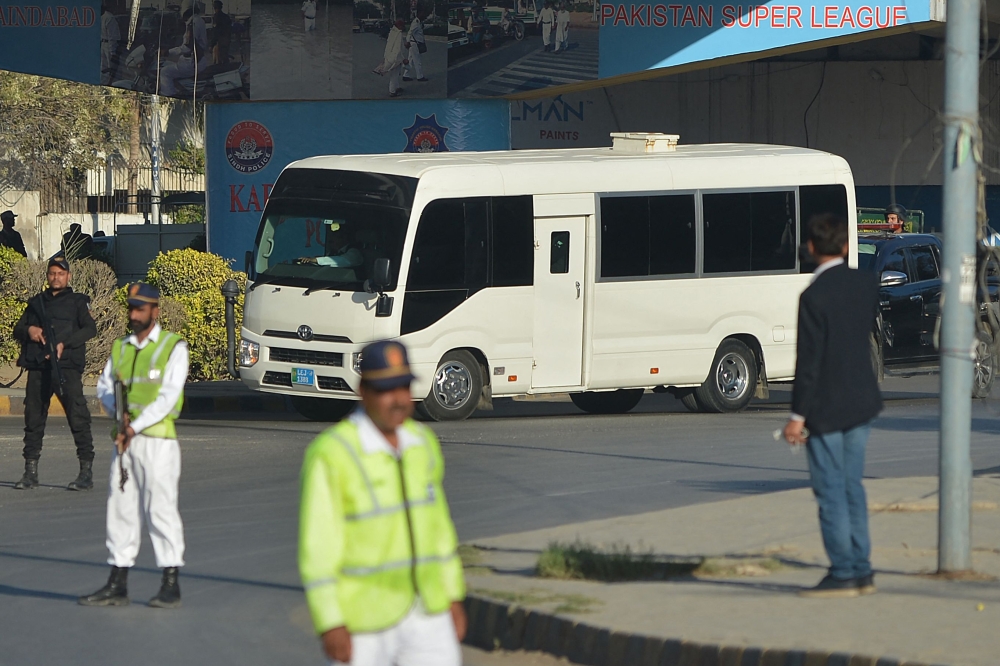 Security personnel cordon off a street as a bus carrying cricketers of 'Karachi Kings' and 'Quetta Gladiators' arrive for Pakistan Super League (PSL) T20 cricket match at the National Stadium in Karachi on February 18, 2023. (Photo by Rizwan TABASSUM / AFP)