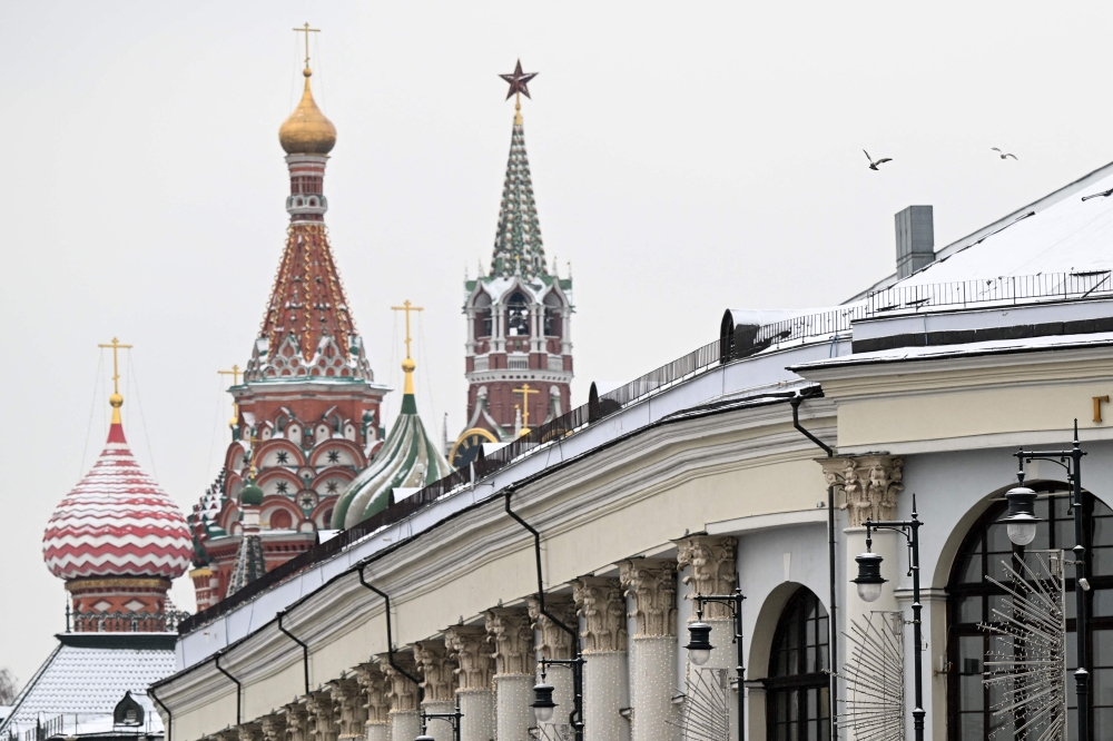 Pigeons fly above the Gostiny Dvor conference centre, the venue for tomorrow's Russian President Vladimir Putin's annual state of the nation address, with the Kremlin's Spasskaya tower and Saint Basil's cathedral on the background, in central Moscow on February 20, 2023. (Photo by Kirill KUDRYAVTSEV / AFP)
