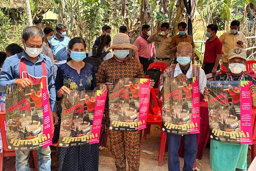 This picture released by Cambodia's Communicable Disease Control Department (CDCD) on February 23, 2023, shows villagers posing with posters about H5N1 virus threats, in Prey Veng province. Photo by Handout / Cambodia's Communicable Disease Control Department / AFP