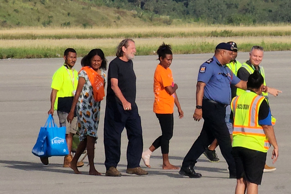 Bryce Barker (C), who was held for a week in the Papua New Guinea highlands by an armed group, is escorted from a plane following his release in Port Moresby on February 26, 2023. (Photo by AFP)
