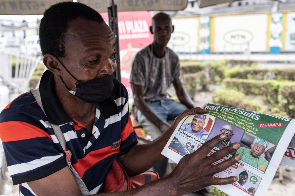 A man points at a newspaper in Lagos, on February 26, 2023, the day after Nigeria's presidential and general election. (Photo by John Wessels / AFP)