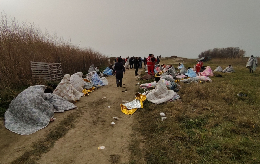This photo obtained from Italian news agency Ansa, taken on February 26, 2023 shows rescued migrants wrapped in a blanket in Steccato di Cutro, south of Crotone, after their boat sank off Italy's southern Calabria region. (Photo by STRINGER / ANSA / AFP) 