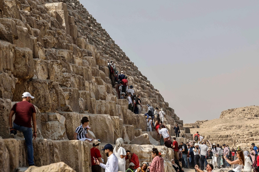 Tourists visit the Great Pyramid of Khufu (Cheops) at the Giza Pyramids necropolis on the southwestern outskirts of Cairo, on March 2, 2023. - A hidden corridor of 9 metre-long has been spotted close to the main entrance of the pyramid, a discovery made under the Scan Pyramids project that has been in place since 2015, Egyptian antiquities officials announced on March 2. (Photo by Khaled DESOUKI / AFP) 