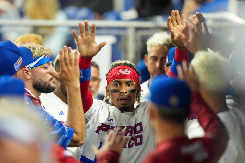 MIAMI, FLORIDA - MARCH 13: Francisco Lindor #12 of Puerto Rico is congratulated by teammates after scoring on a double hit by Enrique Hernandez #5 in the second inning against Israel at loanDepot park on March 13, 2023 in Miami, Florida. Eric Espada/Getty Images/AFP (Photo by Eric Espada / GETTY IMAGES NORTH AMERICA / Getty Images via AFP)
