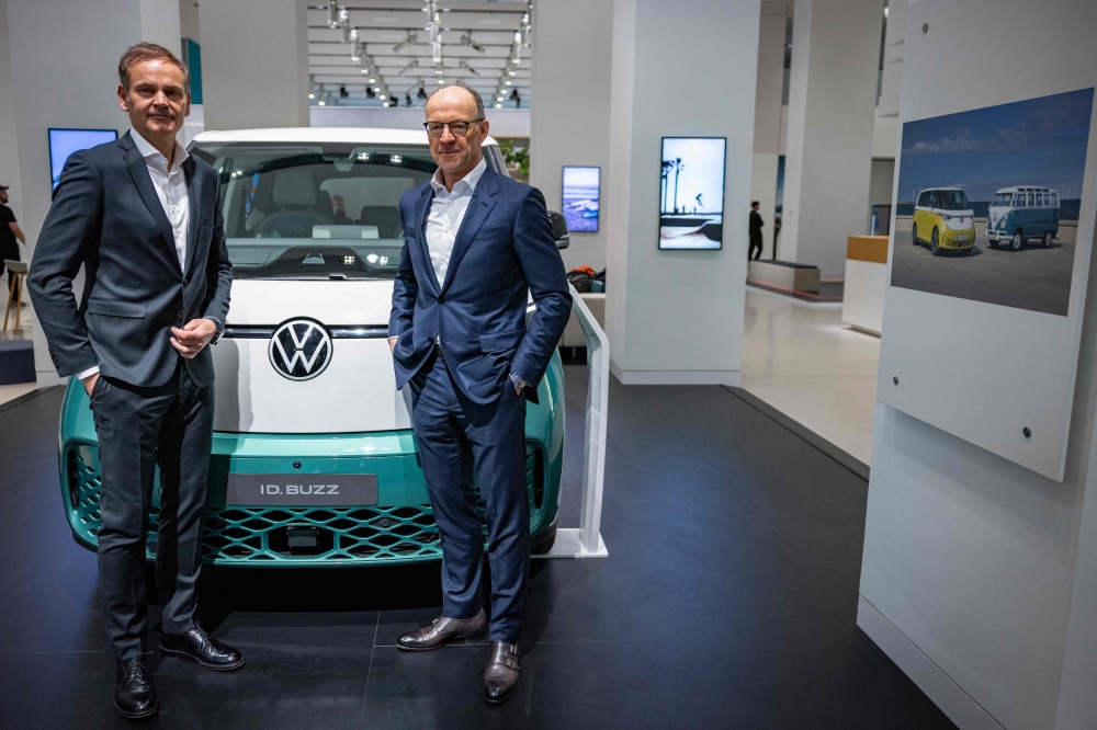 Oliver Blume (left), CEO of German car giant Volkswagen (VW), and VW CFO & COO Arno Antlitz stand in front of a Volkswagen ID Buzz van on the sidelines of their company's annual press conference to present the business report, on March 14, 2023 in Berlin.  (Photo by Odd ANDERSEN / AFP)