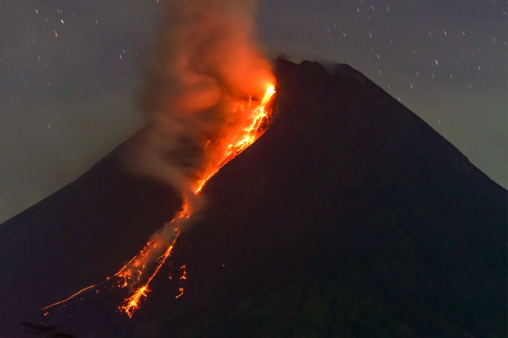 Mount Merapi volcano spews lava from its crater as seen from Sleman in Yogyakarta early on March 18, 2023. (Photo by Devi Rahman / AFP)