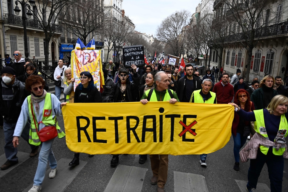 Protesters participate in a march holding a banner which reads as 