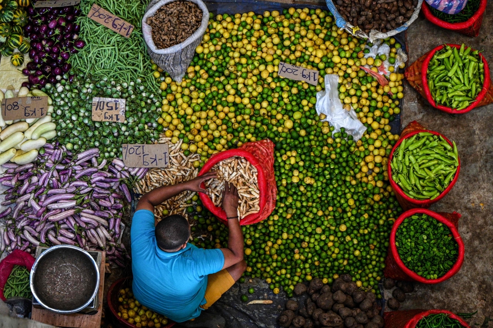 A vendor arranges vegetables as he waits for customers at a market in Colombo on March 21, 2023. - Sri Lanka must not allow entrenched corruption to undermine a bailout for its bankrupt economy, the IMF said on March 21, 2023 after signing off on a $3 billion loan for the crisis-hit nation. (Photo by ISHARA S. KODIKARA / AFP)